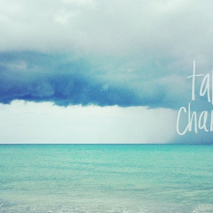 May include: A motivational quote, "take chances", written in white against a backdrop of a stormy sky over a turquoise ocean.