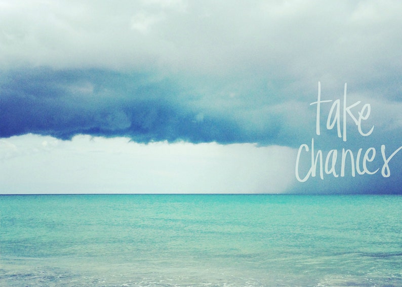 May include: A motivational quote, "take chances", written in white against a backdrop of a stormy sky over a turquoise ocean.