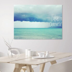 May include: A canvas print with a blue and white seascape and the text "take chances" in white.