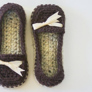 May include: A pair of brown crocheted slippers with a white crocheted trim and a white satin bow on each slipper.