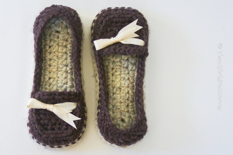 May include: A pair of brown crocheted slippers with a white crocheted trim and a white satin bow on each slipper.