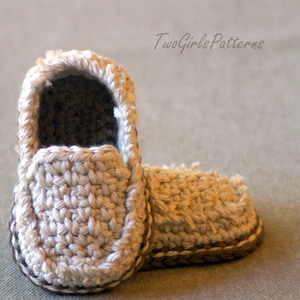 May include: A pair of crocheted baby shoes in a beige color. The shoes have a simple design and are made with a soft yarn.