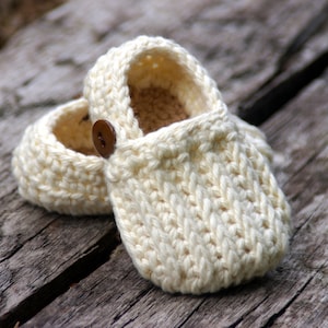 May include: A pair of crocheted baby booties in a cream color with a brown button on one bootie.