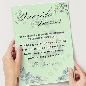 Puede incluir: Un libro verde claro con las palabras "Querido Precursor" en escritura elegante. El libro tiene detalles florales y texto en español, incluyendo "Te admiramos y te queremos mucho por tu espiritu de sacrificio."