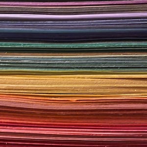 Side edges of a stack of construction paper arranged in a rainbow, red to purple bottom to top.