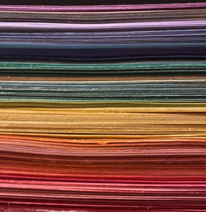 Side edges of a stack of construction paper arranged in a rainbow, red to purple bottom to top.