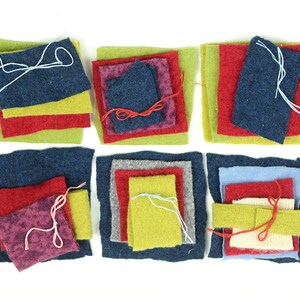 May include: Six stacks of assorted square fabric swatches in various colors including navy blue, lime green, red, magenta, gray, and light blue. Each stack is secured with a thin piece of white, red, or light blue thread tied in a simple knot.