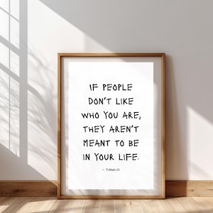 Könnte beinhalten: Ein gerahmter Druck mit dem Zitat "IF PEOPLE DON'T LIKE WHO YOU ARE, THEY AREN'T MEANT TO BE IN YOUR LIFE." in schwarzer Schrift. Der Druck befindet sich in einem Holzrahmen und lehnt an einer weißen Wand. Der Autorname, YUNGBLUD, steht unten.