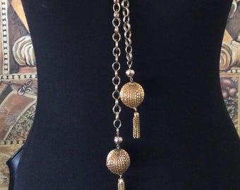 Collar largo tipo lariat con borla, estilo vintage, en tono dorado, joyería de los años 50 y 60.