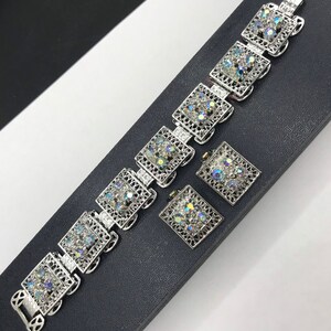 Pu&ograve; includere: Un braccialetto d'argento con un delicato design a filigrana e strass iridescenti. Il braccialetto &egrave; abbinato a un set di orecchini abbinati.