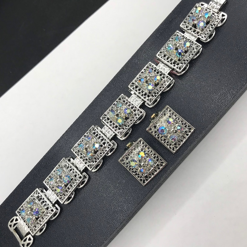 Pu&ograve; includere: Un braccialetto d'argento con un delicato design a filigrana e strass iridescenti. Il braccialetto &egrave; abbinato a un set di orecchini abbinati.