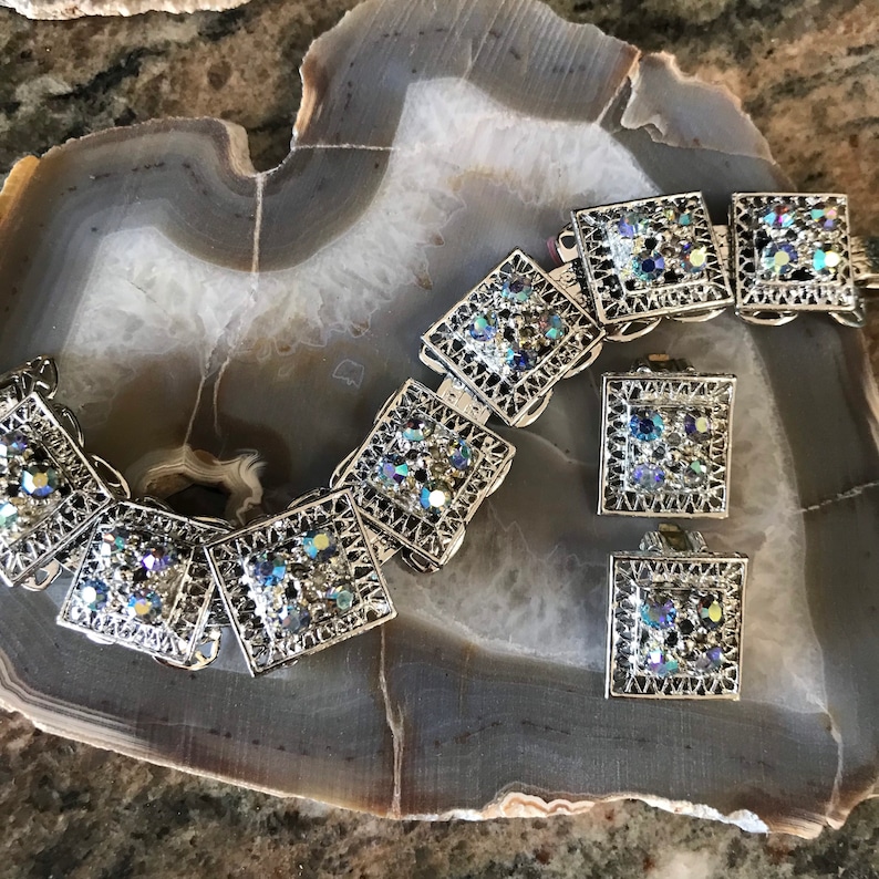 Pu&ograve; includere: Un braccialetto color argento con un delicato design a filigrana e strass blu iridescenti. Il braccialetto &egrave; abbinato a un paio di orecchini.
