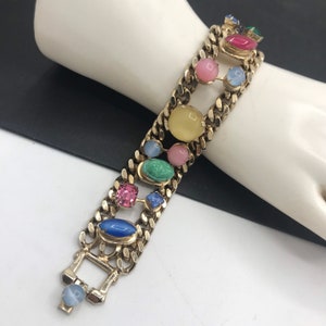 May include: A gold chain bracelet with colorful oval and square shaped stones. The stones are in shades of blue, green, pink, yellow, and red.