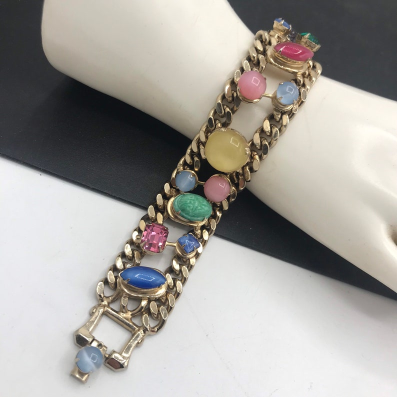 May include: A gold chain bracelet with colorful oval and square shaped stones. The stones are in shades of blue, green, pink, yellow, and red.
