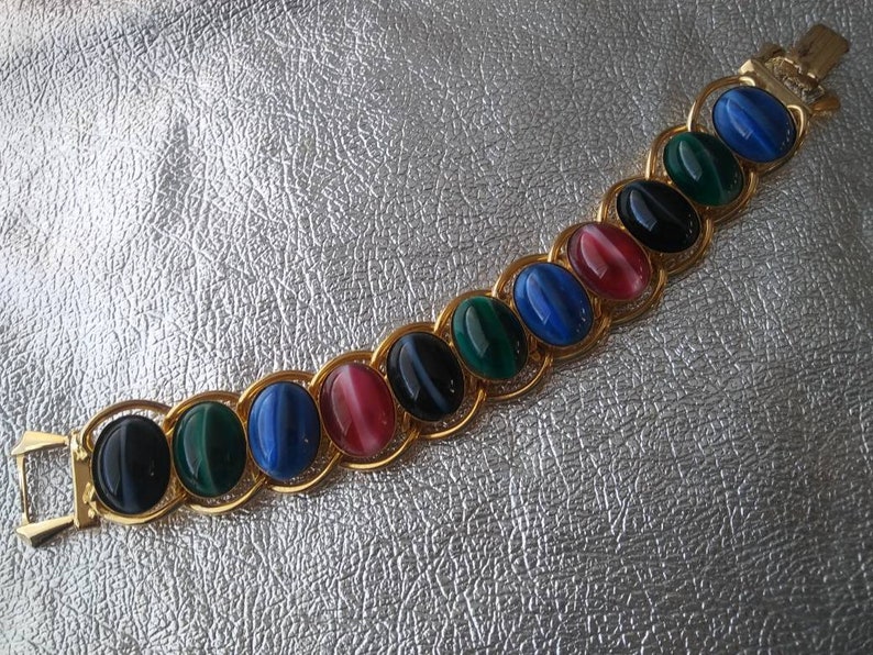 May include: A gold chain bracelet with oval-shaped gemstones in shades of blue, green, black, and pink.