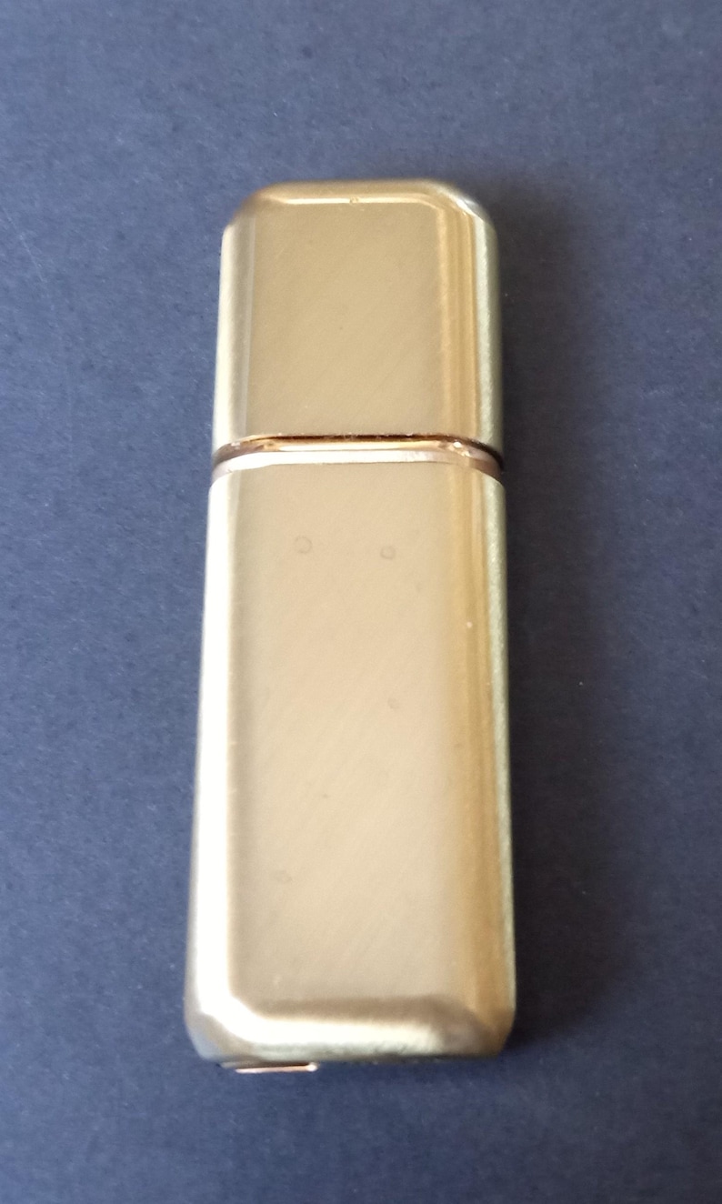 May include: A gold metal perfume bottle with a rectangular shape.
