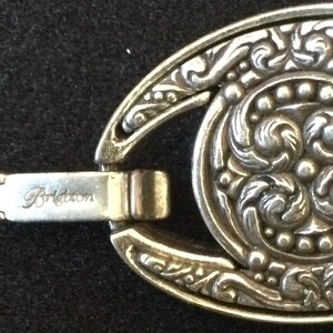 Peut inclure: Gros plan sur un fermoir de bracelet Brighton argent&eacute;. Le fermoir pr&eacute;sente un design ovale avec des motifs floraux et volutes complexes. Le mot "Brighton" est grav&eacute; sur le fermoir.