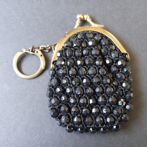 May include: A small black beaded coin purse with a gold metal clasp and a key ring attached.