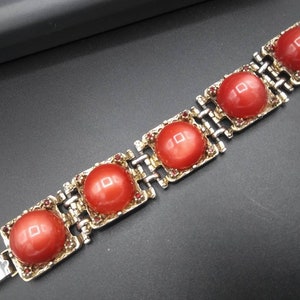 May include: A vintage bracelet featuring five large, round, coral-colored cabochons set in gold-toned metal frames. The bracelet has a silver-toned chain link design and is accented with small red rhinestones. The clasp is silver-toned.