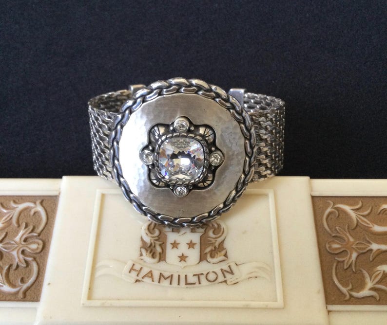 May include: A white ceramic mug with a black handle and the text "But First, Coffee" in a handwritten style. The mug is on a white surface. The mug is approximately 4 inches tall.