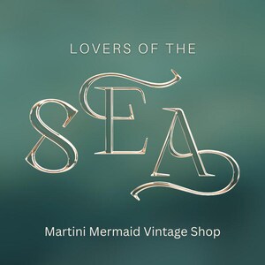 May include: A graphic design featuring the text LOVERS OF THE SEA in a metallic gold serif font with elegant flourishes, centred above the text Martini Mermaid Vintage Shop, all set against a solid, smooth, dark teal gradient background.