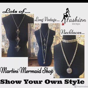 Może przedstawiać: Prezentacja długich naszyjnik&oacute;w w stylu vintage na czarnych manekinach. Naszyjniki są w kolorze srebrnym i złotym, z geometrycznymi i łańcuchowymi wzorami. Obraz zawiera tekst "Lots of...", "Long Vintage...", "Fashion Boutique", "Necklaces...", "Martini Mermaid Shop" i "Show Your Own Style."