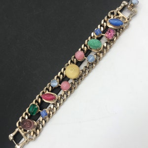 May include: A gold chain bracelet with colorful oval-shaped stones. The stones are in shades of pink, blue, green, and yellow.