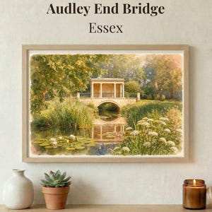 May include: A framed watercolor print of Audley End Bridge in Essex. The artwork depicts a stone bridge over a pond, surrounded by lush greenery and white flowers. The print is in a light wooden frame, with text at the top.