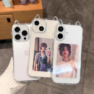 May include: Three clear phone cases with cat ear accents. Two cases feature photos of a person, and one is plain. The cases are designed to fit a smartphone and have a clear, protective design.