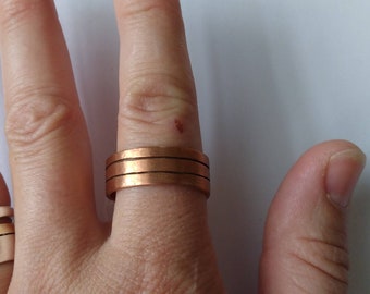 May include: A copper ring with three bands. The ring is worn on a finger.