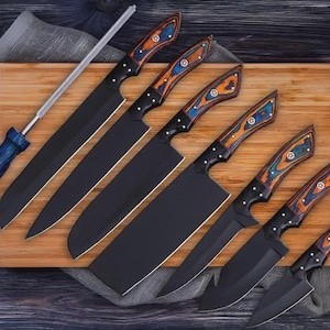 Könnte beinhalten: Ein Set aus sechs schwarzen Küchenmessern mit Holzgriffen mit blauen und orangefarbenen Akzenten, präsentiert auf einem Holzschneidebrett. Enthält einen Wetzstahl. Die Messer variieren in Größe und Form.