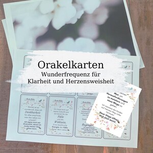 May include: A set of oracle cards with the text "Orakelkarten Wunderfrequenz f&uuml;r Klarheit und Herzensweisheit". The cards have floral designs and inspirational quotes. The image has a soft, blurred background.