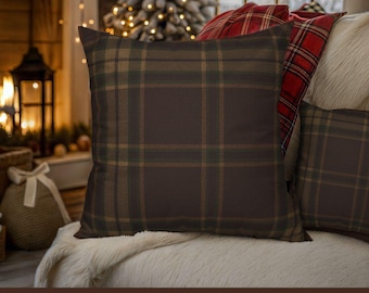 May include: Brown plaid pillow cover with a classic plaid pattern in shades of brown, green, and tan. The pillow is square-shaped and rests on a white, fluffy surface. The text "Brown Plaid Pillow Cover" is at the bottom.