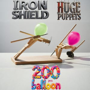 May include: Two wooden catapult toys, one with a green balloon and the other with a pink balloon. The image features the text "IRON SHIELD" and "HUGE PUPPETS". The text "200 pcs balloon" is also visible.