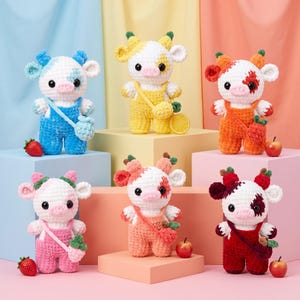 May include: Six crocheted cow plushies in various colors including blue, yellow, orange, pink, peach, and red. Each cow wears matching overalls and a crossbody bag, featuring black eyes, pink snouts, and small fruit accents like strawberries.