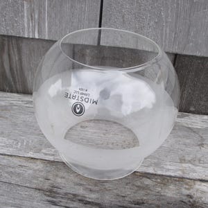 May include: A clear glass globe lamp shade with a spherical shape and a wide circular opening at the bottom. The glass features a frosted lower section and black printed text that reads MIDSTATE LAMP LLC #1324 with a circular logo icon.