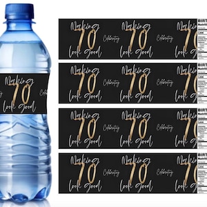 Op de afbeelding: Een heldere waterfles met een blauwe dop en een zwart etiket met de gouden tekst "Making 70 Look Good". Extra labels met dezelfde tekst en "Birthday Nutrition Facts" zijn ook zichtbaar.