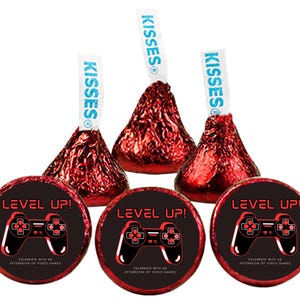 May include: Red foil-wrapped chocolate candies with white paper tags that read "KISSES". Three candies are paired with round stickers that say "LEVEL UP!" with a video game controller graphic. The stickers also say "Celebrate with an afternoon of video games."