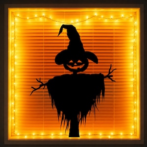 May include: A black silhouette of a scarecrow wearing a pointed hat and a pumpkin head with a carved face. The figure is positioned against a window covered by orange horizontal blinds and framed by a string of warm white glowing fairy lights.