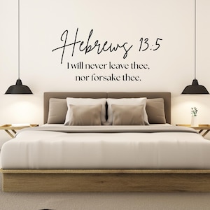 May include: A bedroom scene featuring a bed with a wooden frame and neutral-toned bedding. Above the bed, the text "Hebrews 13:5 I will never leave thee, nor forsake thee" is displayed. Black pendant lights hang on either side.