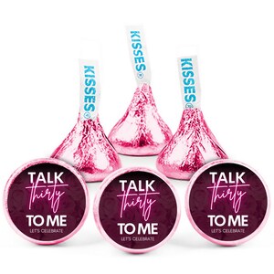 May include: Pink foil-wrapped Hershey's Kisses candies with blue paper flags. Below are round stickers with the text "TALK THIRTY TO ME" in white and pink, with "LET'S CELEBRATE" below.