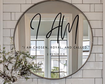 Op de afbeelding: Een ronde spiegel met een zwart frame. De woorden "I AM" staan in sierlijke letters op de spiegel. Daaronder staat de tekst "I AM CHOSEN, ROYAL, AND CALLED." 1 PETER 2:9. De spiegel reflecteert een raam.