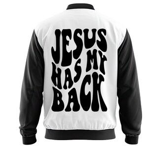 May include: A white and black varsity jacket featuring the text "JESUS HAS MY BACK" in large, black, bubble letters on the back. The jacket has black sleeves, trim, and a collar.