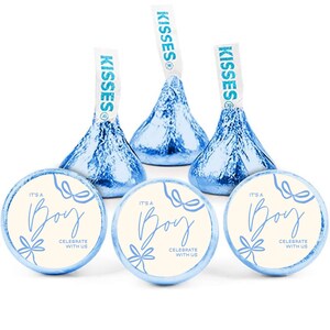 May include: An arrangement of blue foil-wrapped chocolate candies and round stickers. The stickers read "It's a Boy" with bow illustrations and the text "Celebrate with Us". The candies have "Kisses" paper tags.