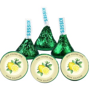 May include: Three Hershey's Kisses candies wrapped in green foil, with white paper tags that read "KISSES". Below are three round stickers with a lemon and mint design, and the text "SHE FOUND HER MAIN SQUEEZE".