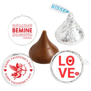 May include: A close-up of Hershey's Kisses chocolates with various Valentine's Day-themed wrappers. The wrappers feature phrases like "Be Mine" and "Love," along with a cupid illustration. The chocolates are in silver foil and brown.