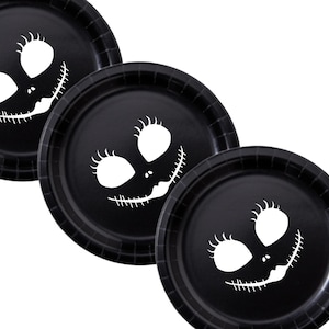 May include: Three black paper plates with a white Jack Skellington face design. The plates have a ridged edge and are arranged at a slight angle against a white background. Perfect for a Halloween or Nightmare Before Christmas themed party.