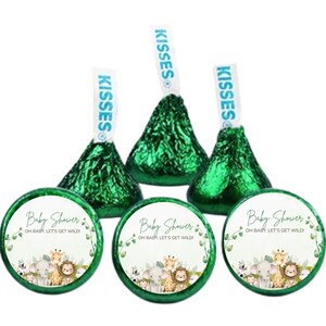 May include: Three Hershey's Kisses candies with green foil wrappers and blue and white paper labels. Below are three round stickers with a jungle animal theme and the text "Baby Shower, Oh Baby, Let's Get Wild!"