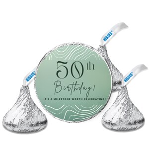 May include: An image of three Hershey's Kisses candies with a custom label. The label is a light green circle with the text "50th Birthday!" and "It's a milestone worth celebrating!" in black script. The candies are wrapped in silver foil.