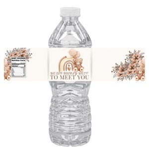 Può includere: Una bottiglia d'acqua di plastica trasparente con un'etichetta personalizzata. L'etichetta presenta un orsacchiotto, un arcobaleno e il testo "We can bearly wait to meet you!" in toni marroni e beige. Tema baby shower.